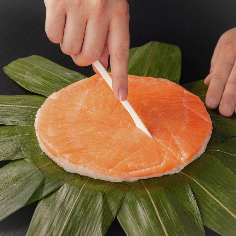 鱒寿司をプラスチックナイフでカットしている画像。