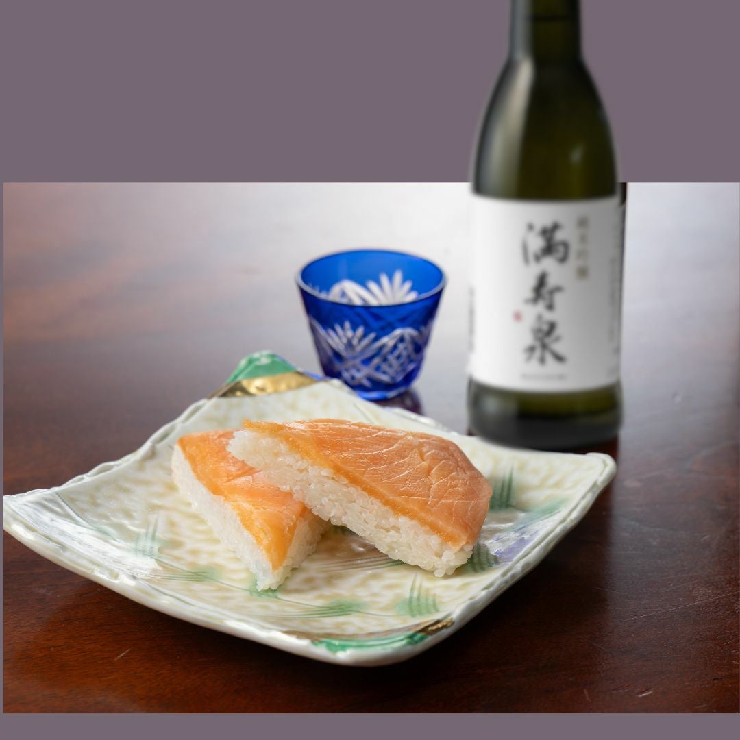 三角にカットされた特選ますのすし２切れと満寿泉、おちょこが載っているイメージ画像です。