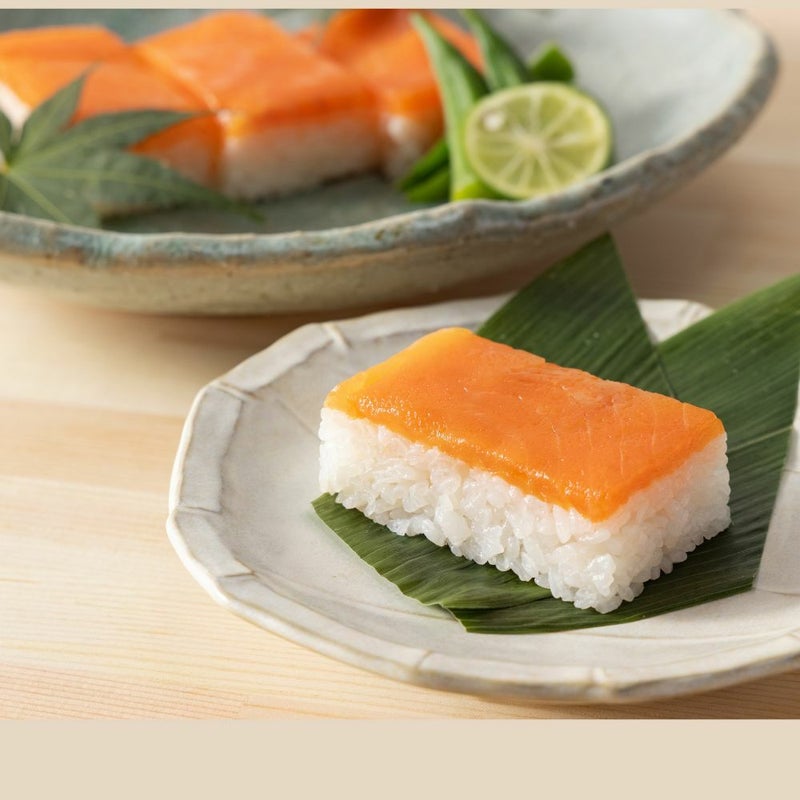 Rejyu（レジュウ）のますがお皿に盛りつけられているイメージ写真です。笹の緑と鱒のオレンジが食卓を彩ります。